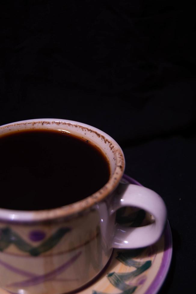 Ein Glas mit gebrühtem schwarzen Kaffee auf schwarzem Hintergrund foto