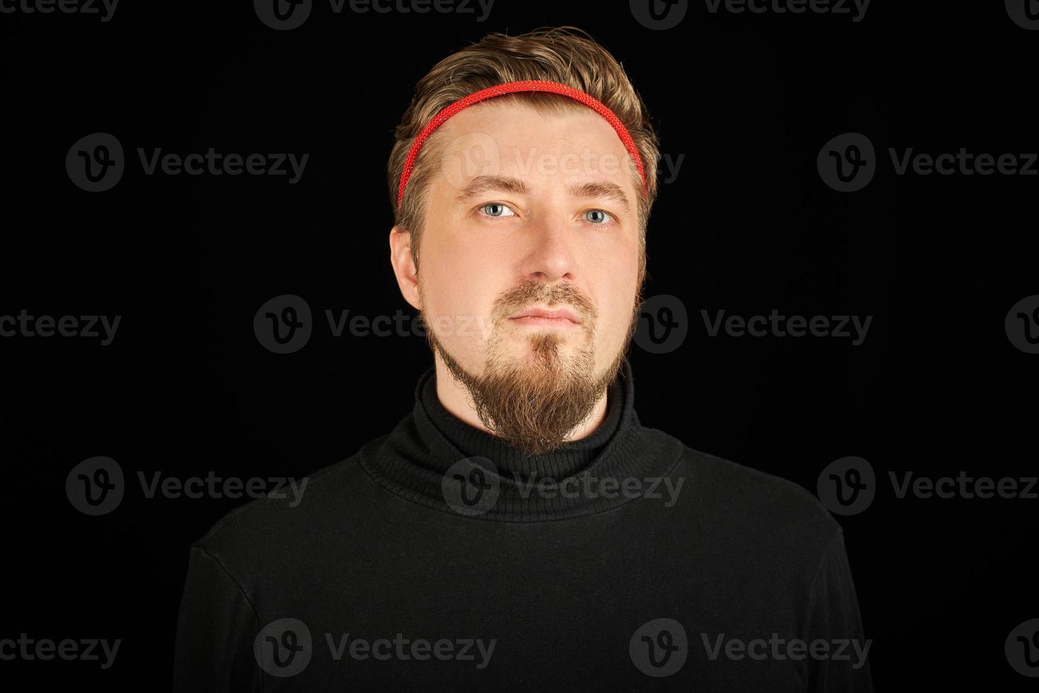 lustiger bärtiger mann mit rotem stirnband, schwarzer hintergrund foto