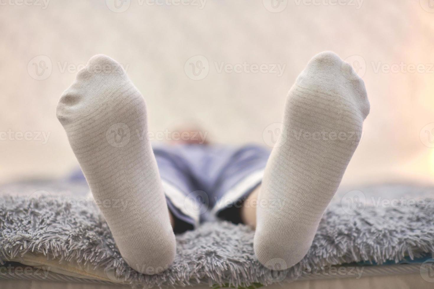 Frau ruht auf dem Sofa in weiß gestreiften Socken, Nahaufnahme. foto