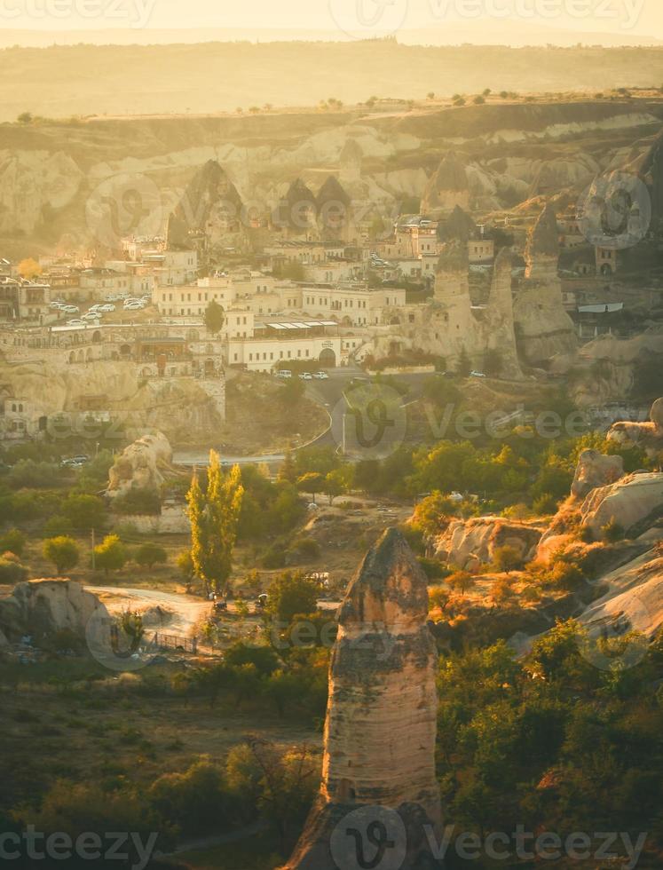 goldener sonnenaufgang über göreme stadt in kappaokien vorderseite sonnenlicht gerichtet mit luftballons in der luft an einem sonnigen dunstigen ruhigen herbstmorgen foto