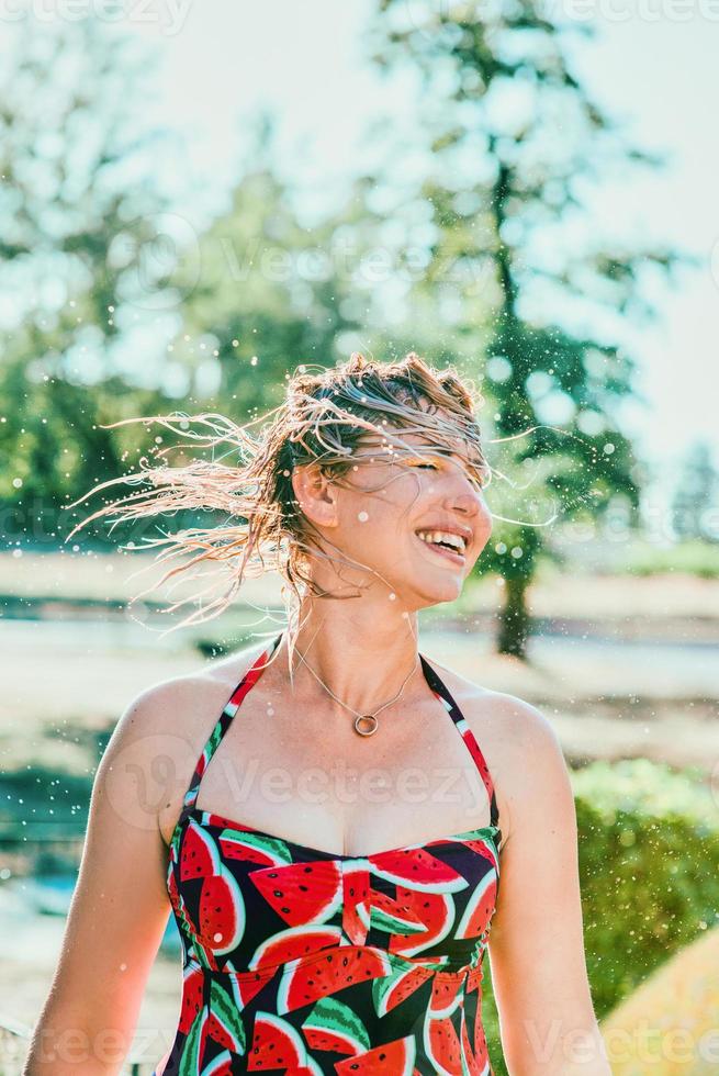 Lachende emotionale blonde Frau mit nassen Haaren, die Wasserspritzer macht. ferien, glück, spaß, sommer, freizeitkonzept foto