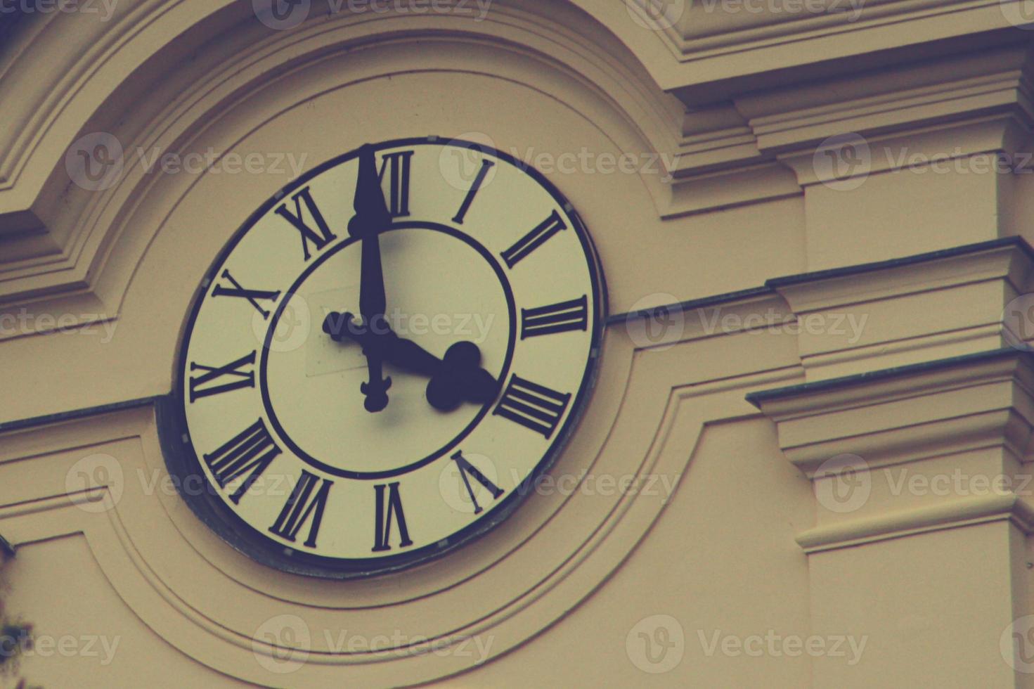 eine Uhr, die an der Seite eines Gebäudes hängt foto