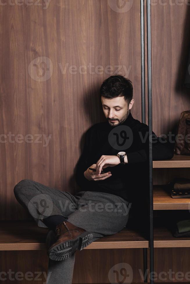 Eleganter Mann sitzt mit einem Telefon foto
