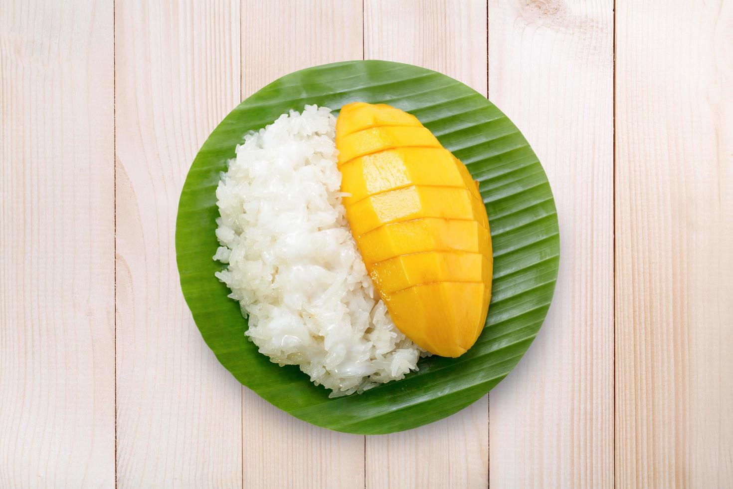 dessert süßer klebriger reis mit mango kokosmilch auf holz foto