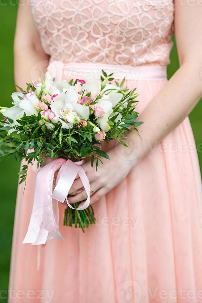 die braut im rosa kleid in der natur mit hochzeits-schönem blumenstrauß aus hellen rosen in verschiedenen farben. gehen die Jungvermählten. Hochzeitstag. der beste Tag eines jungen Paares foto