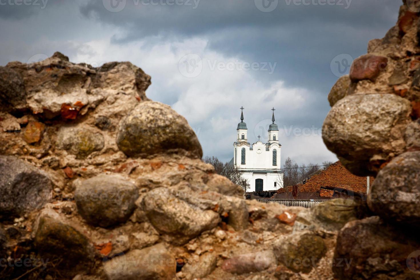 moderner tempel hinter den ruinen einer alten mittelalterlichen burg aus der zeit des großherzogtums litauen in weißrussland an einem bewölkten tag vor dem sturm foto