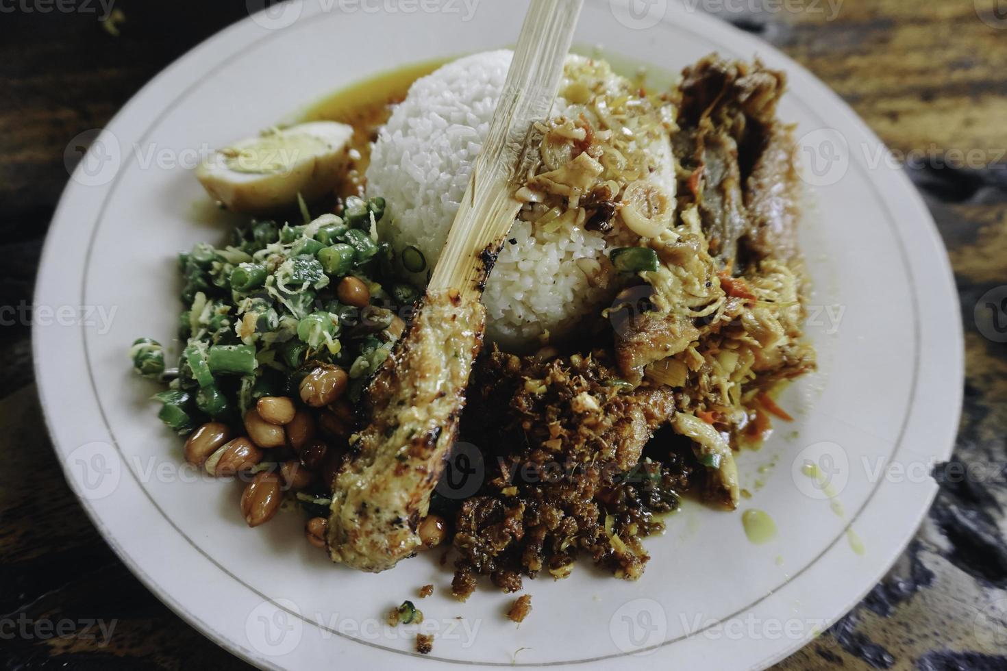 nasi campur ayam betutu. balinesisches Brathähnchen gefüllt mit Maniokblättern. begleitet von gedünstetem Reis, Sate Lilit, Jukut Antungan, Lawar Nangka und Sambal Matah. foto