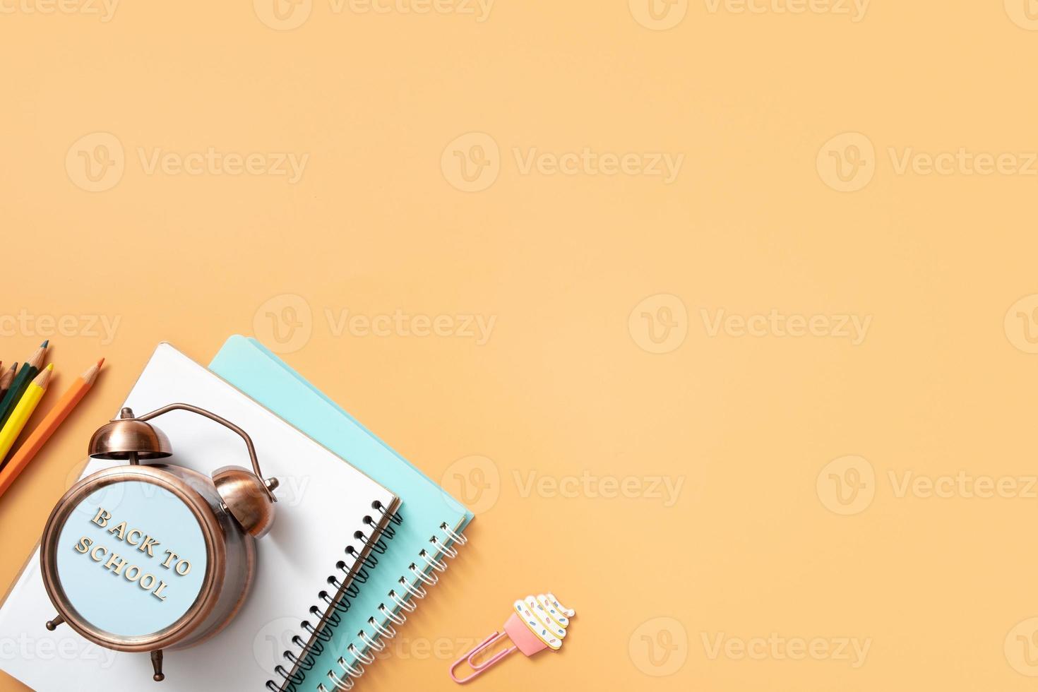 notizbücher, wecker mit zurück zur schule text und stationär auf farbigem hintergrund. Platz kopieren. kinderarbeitsplatz draufsicht, flach liegend foto