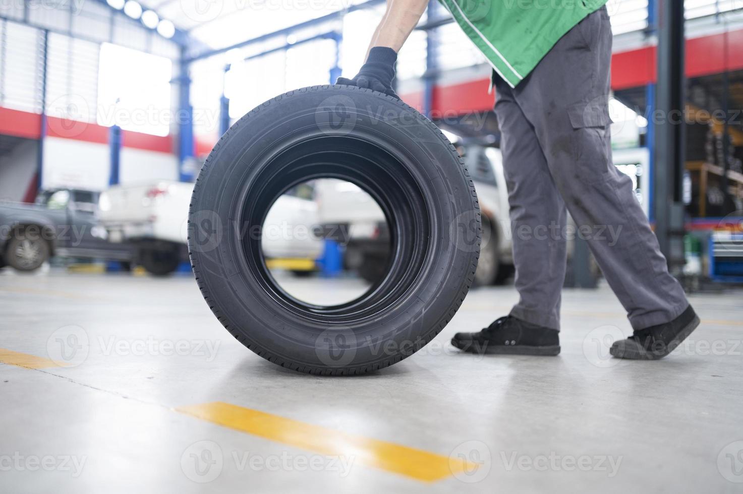 Techniker, der einen Reifen in einer Reifenwechselwerkstatt hält Satz von vier Reifen in einem Autoservice-Center foto