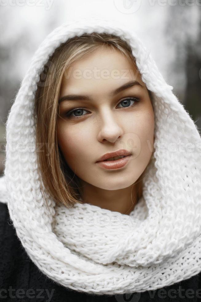 hübsche Frau mit einem weißen Strickschal auf dem Kopf in einem Winterpark foto