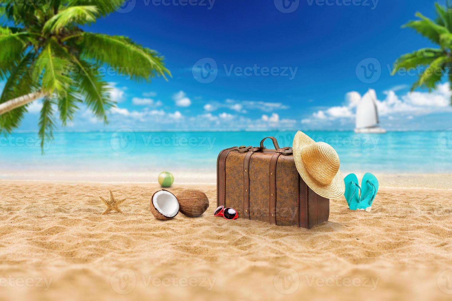 reiseurlaub urlaubskoffer mit sonnenbrille, seestern, strohhut und strandpantoffeln am schönen strand mit palmen. Werbung auf Reisekoffer foto