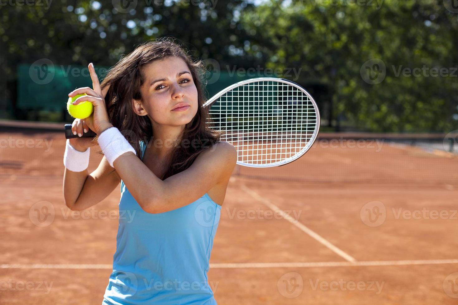 junges Mädchen, das Tennisball auf Platz hält foto