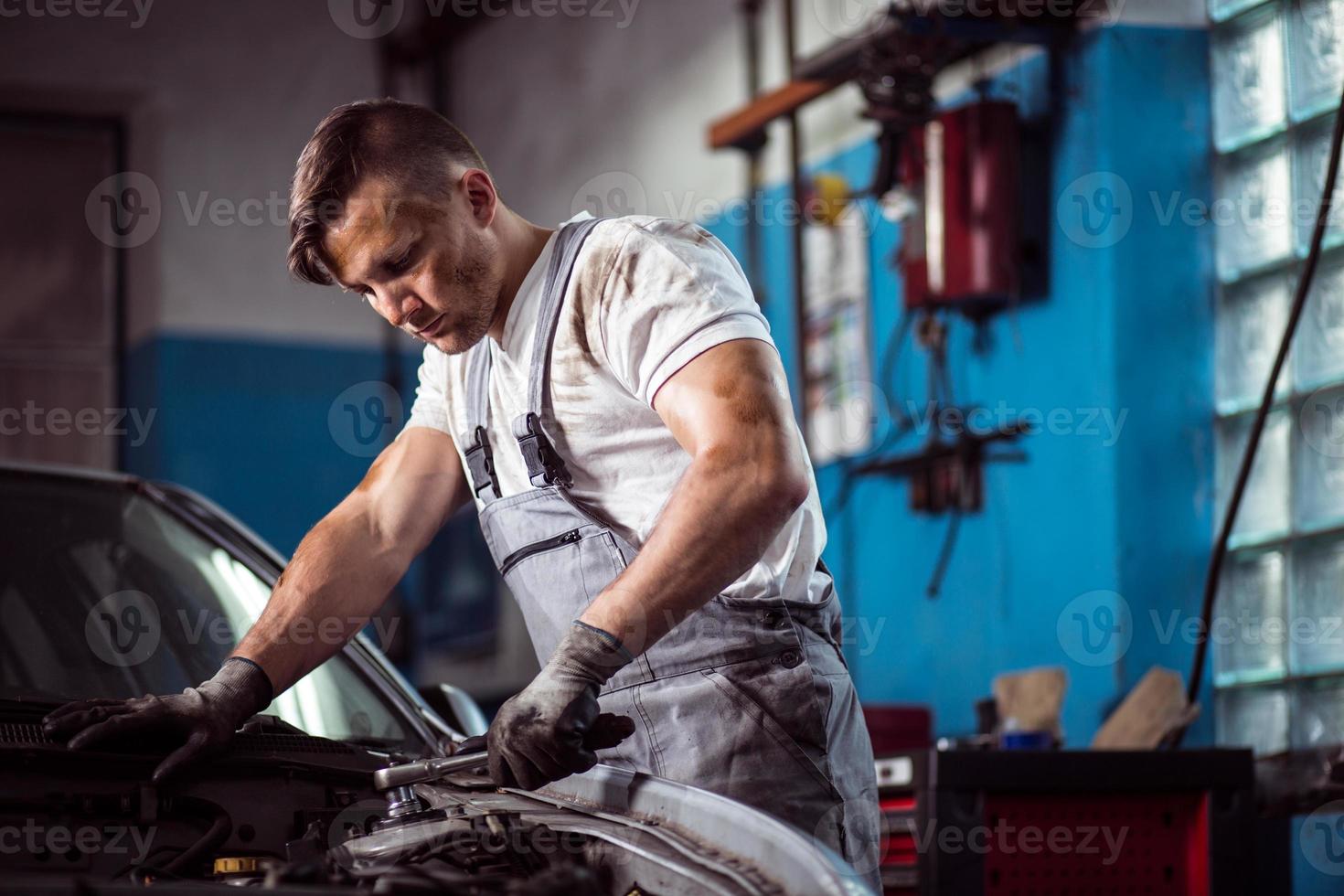 uniformierter Mechaniker in der Tankstelle foto