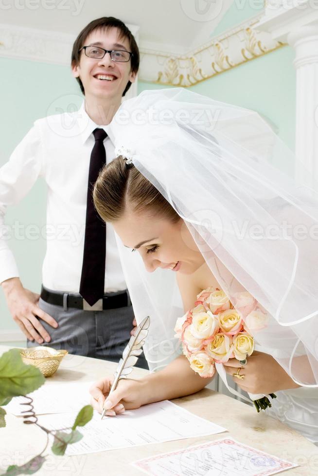 lächelnde Braut unterschreibt Heiratsurkunde foto