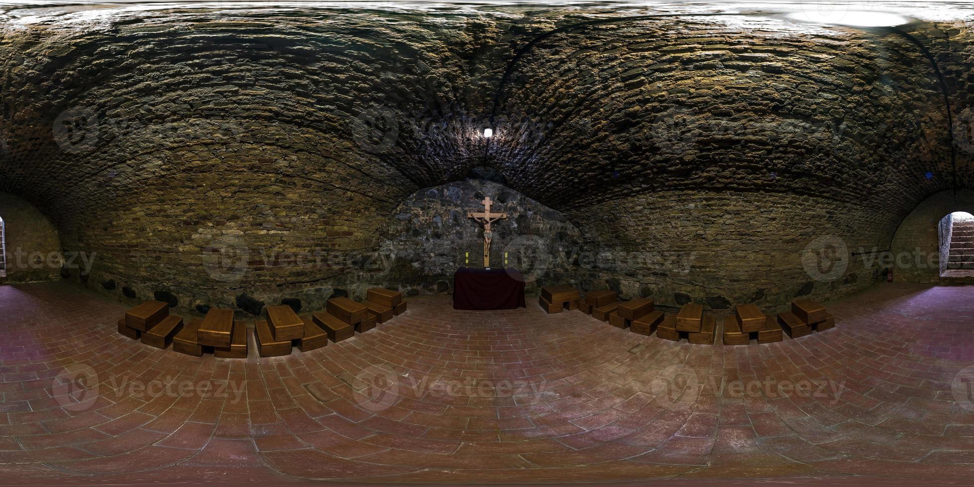Vollständiges nahtloses 360-Grad-Winkelansichtspanorama in der unterirdischen Grotte in der Kirche mit einem Kruzifix auf einer alten Backsteinmauer in äquirechteckiger kugelförmiger Projektion. foto