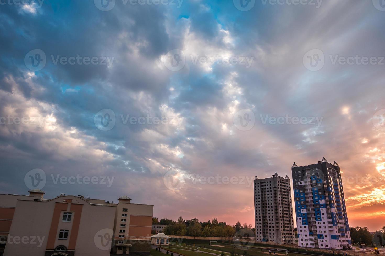 abends flauschige lockige rollende wolken mit fantastischem sonnenuntergang vor dem hintergrund mehrstöckiger wohnhäuser foto