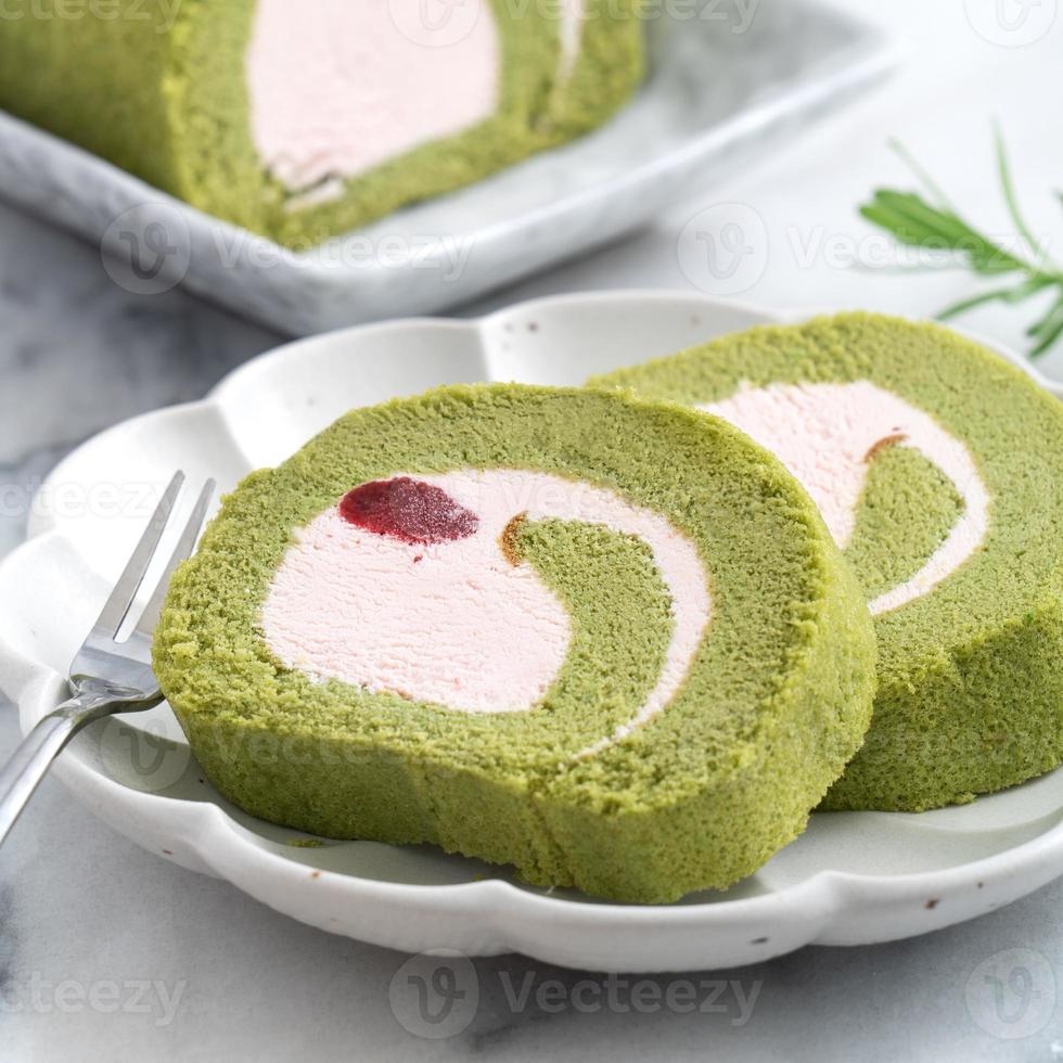 Leckere Matcha Swiss Roll Cake Slices mit Erdbeercreme auf weißem Hintergrund. foto