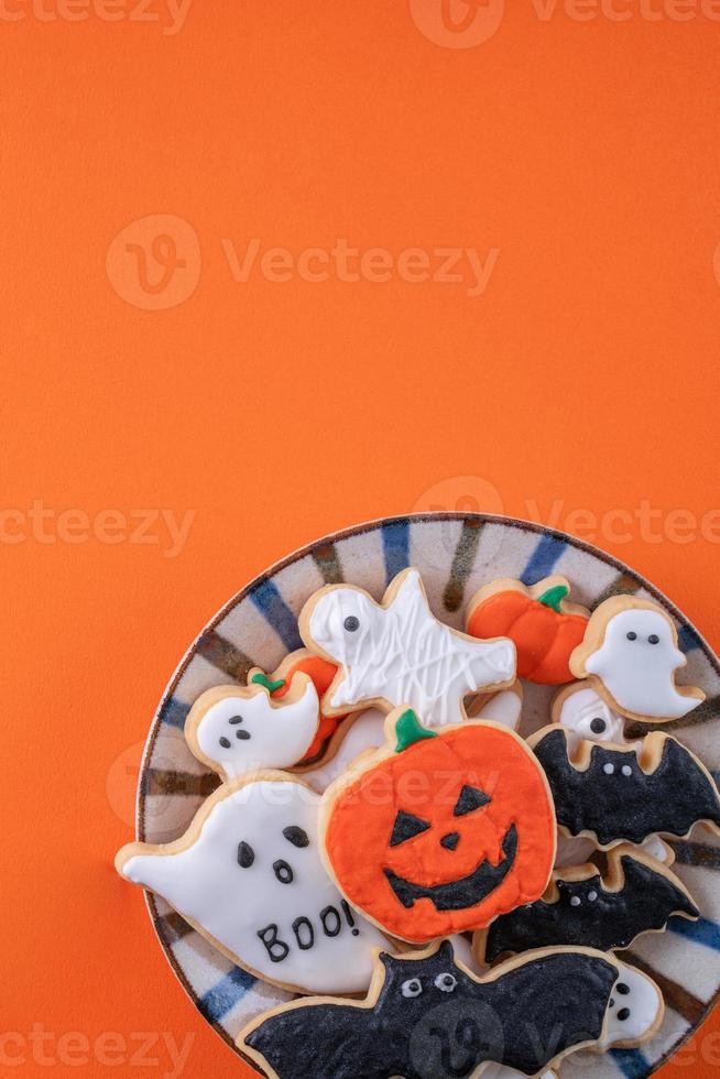 Draufsicht auf Halloween festlich dekorierte Puderzuckerkekse auf orangefarbenem Hintergrund. foto