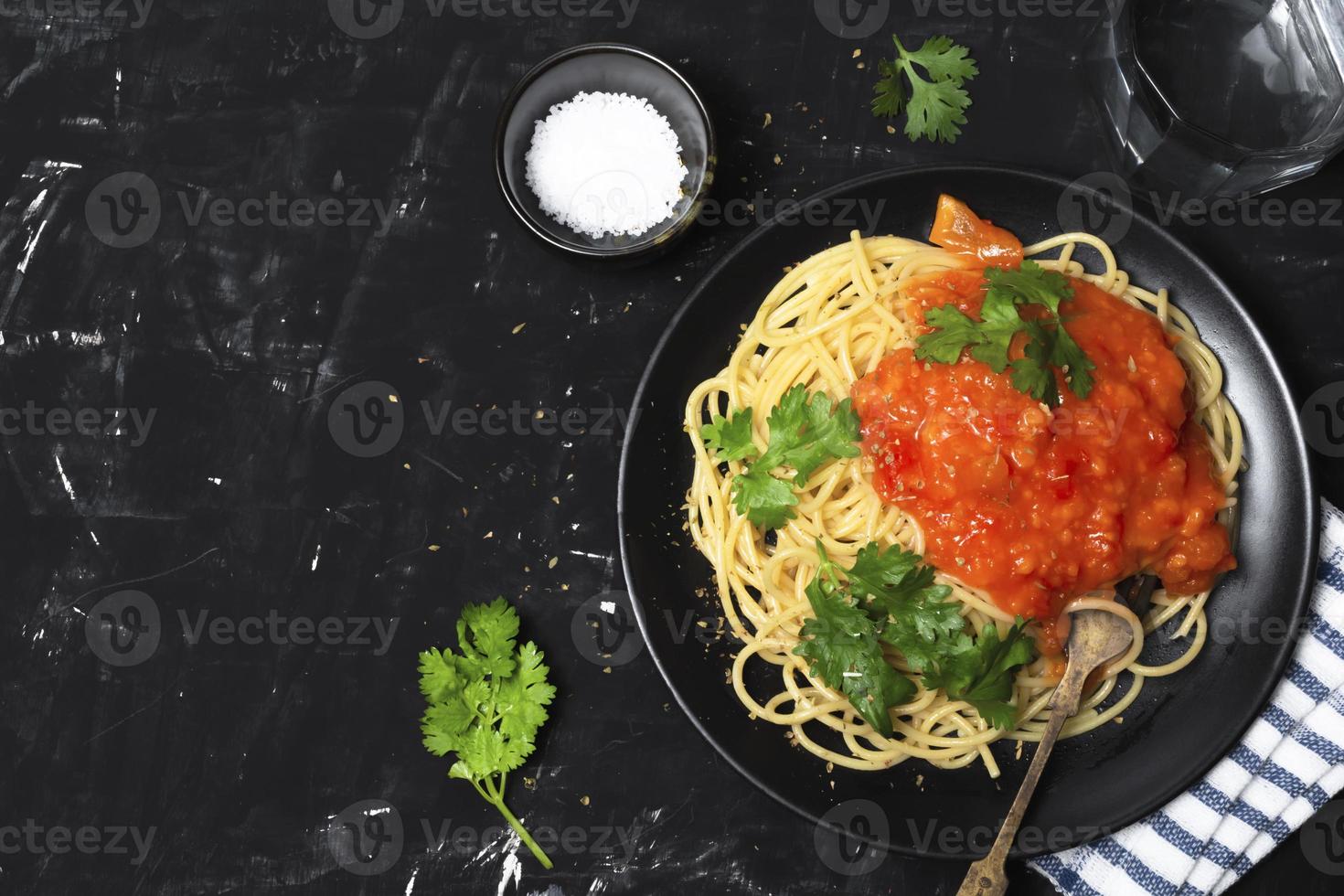 Nudeln mit Tomatensauce in schwarzer Schale auf schwarzem Holzhintergrund foto