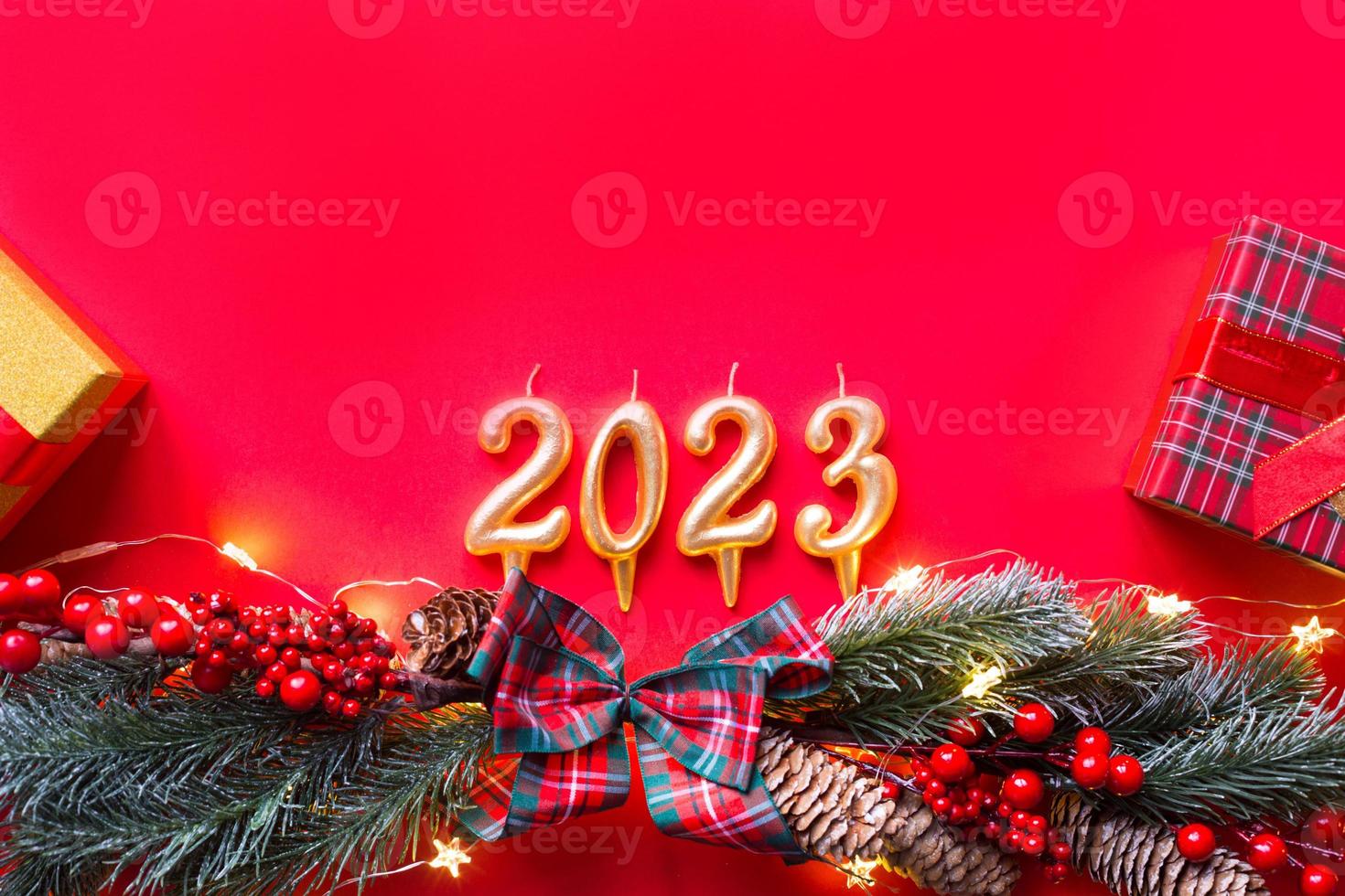 frohes neues jahr - goldene kerzen zahlen 2023 auf rotem hintergrund mit weihnachtsbaum, pailletten, sternen, glitzer, geschenkboxen. Grüße, Postkarte. Kalender, Umschlag. foto