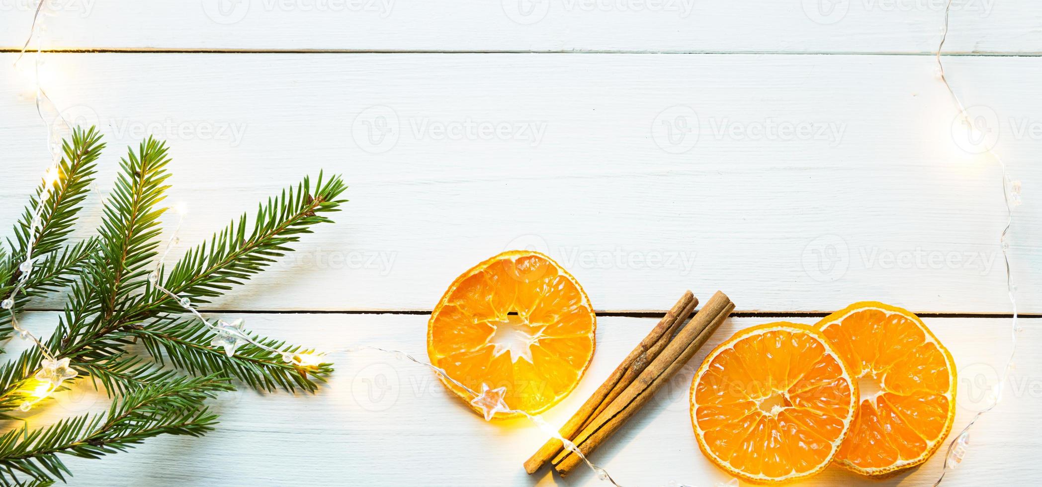 Scheiben getrockneter Orangen, Zimtstangen, Tannenzweige. Lametta und Goldgirlande auf weißem Holzhintergrund. weihnachten, neujahr, urlaub, warme herbst- und winteratmosphäre. kopierraum, flach liegend foto