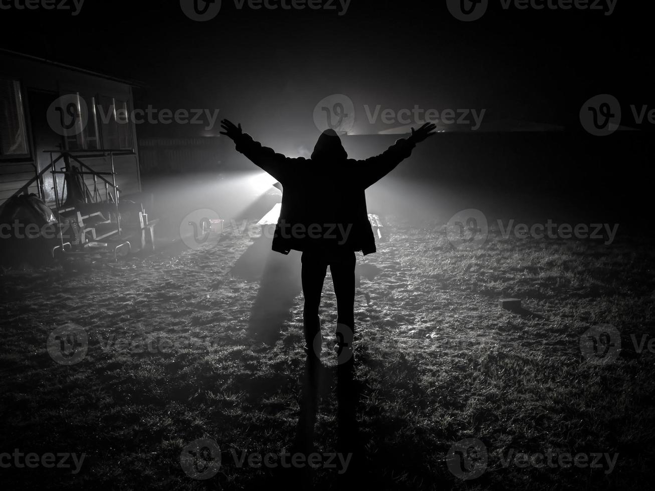 Silhouette des Menschen von der Rückseite mit den Händen im Freien gegen Autolichter foto