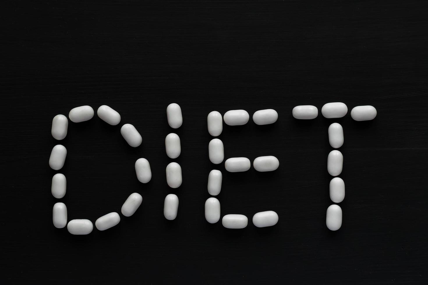 medizinisches Konzept geschrieben mit Pillenwortdiät auf schwarzem hölzernem Hintergrund mit Kopienraum foto