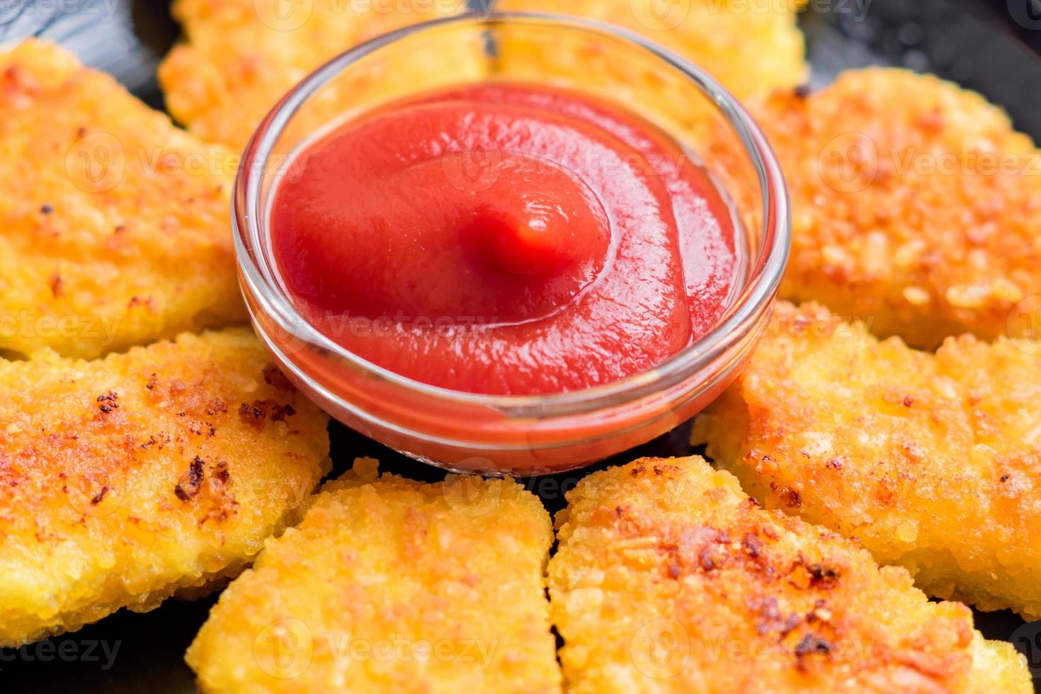 frittierte knusprige Chicken Nuggets mit Ketchup auf schwarzem Teller foto