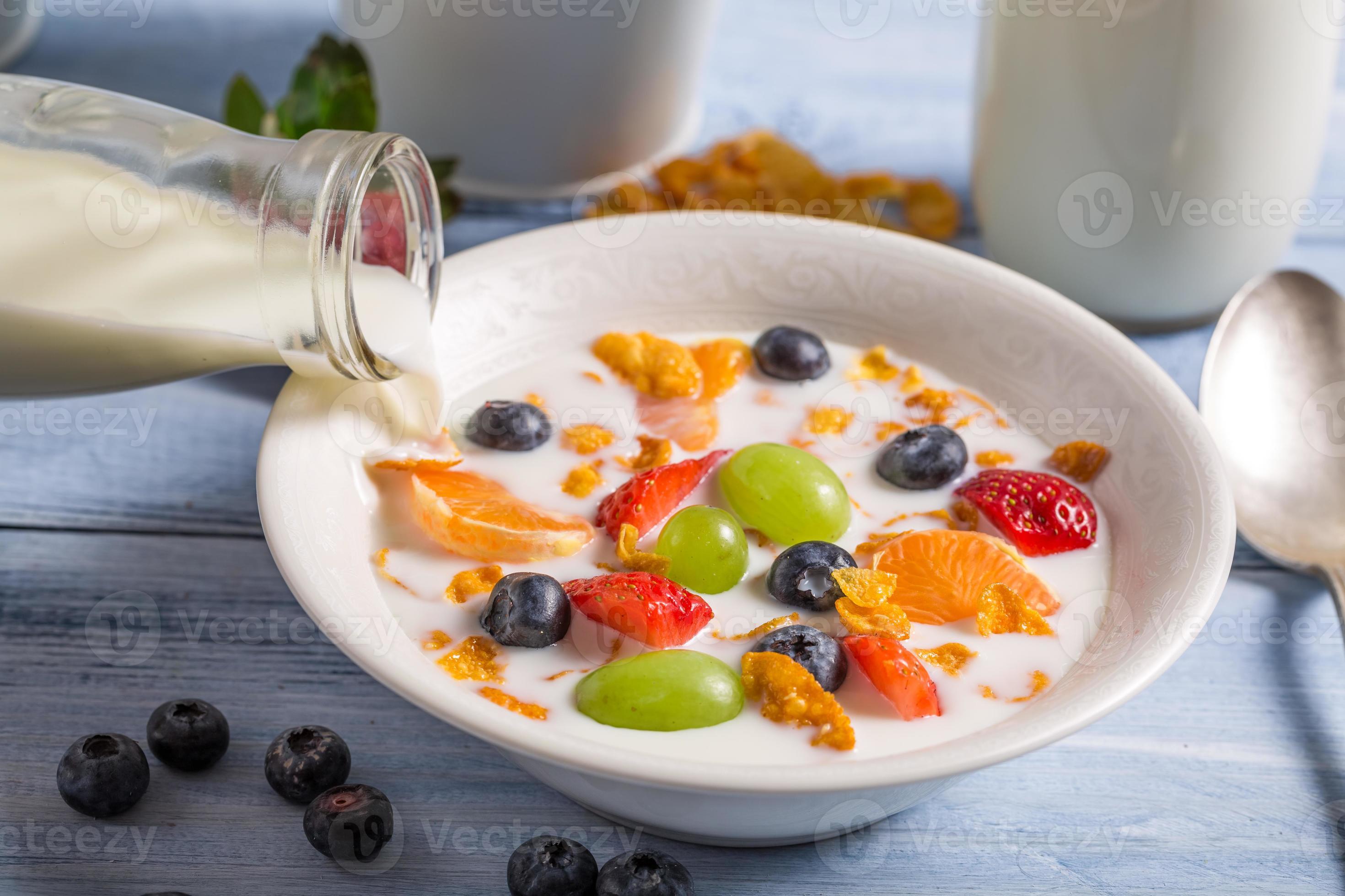 Gießen von Milch auf Cornflakes mit Früchten foto