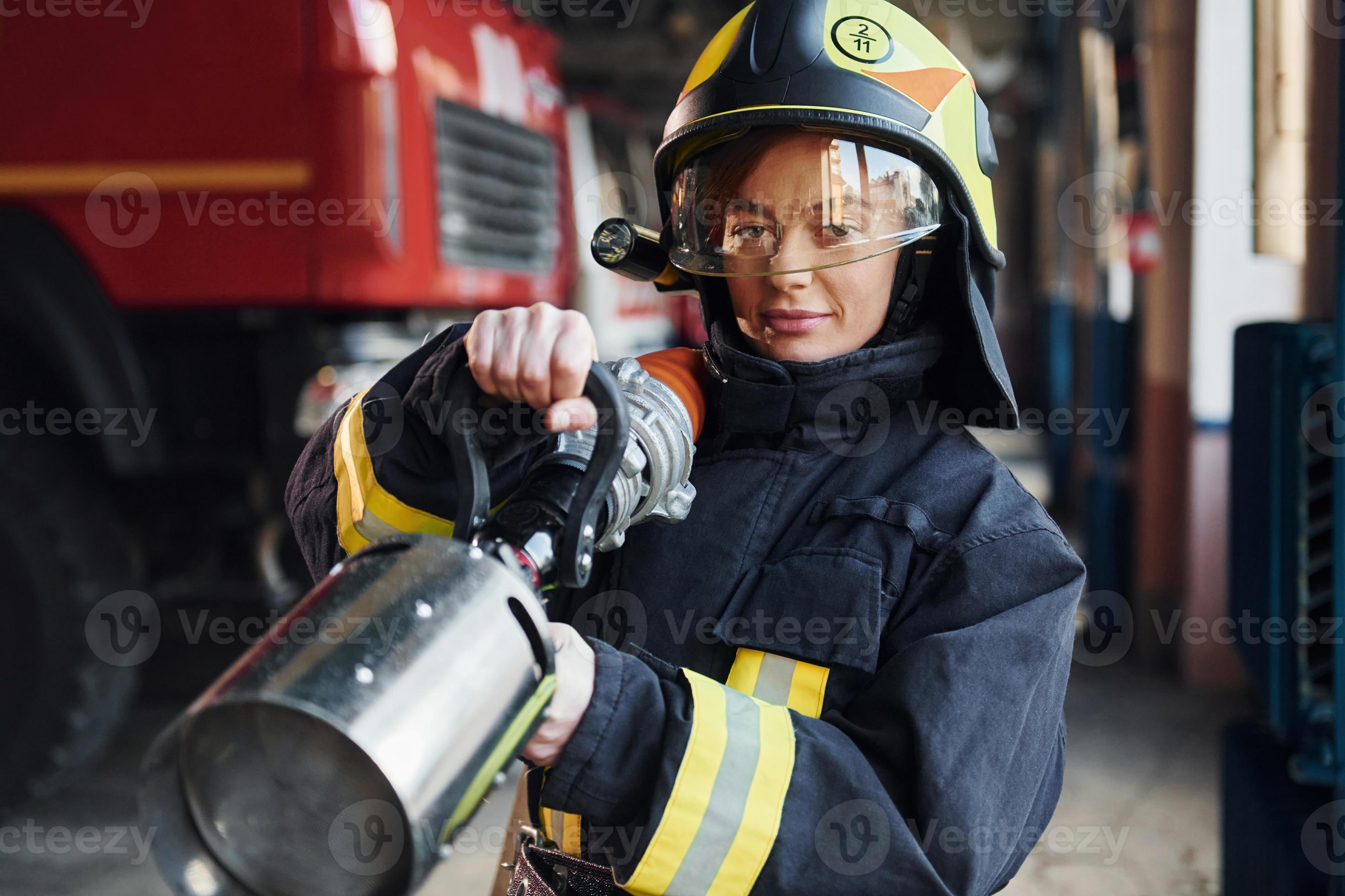 Schlauch in den Händen. weiblicher feuerwehrmann in