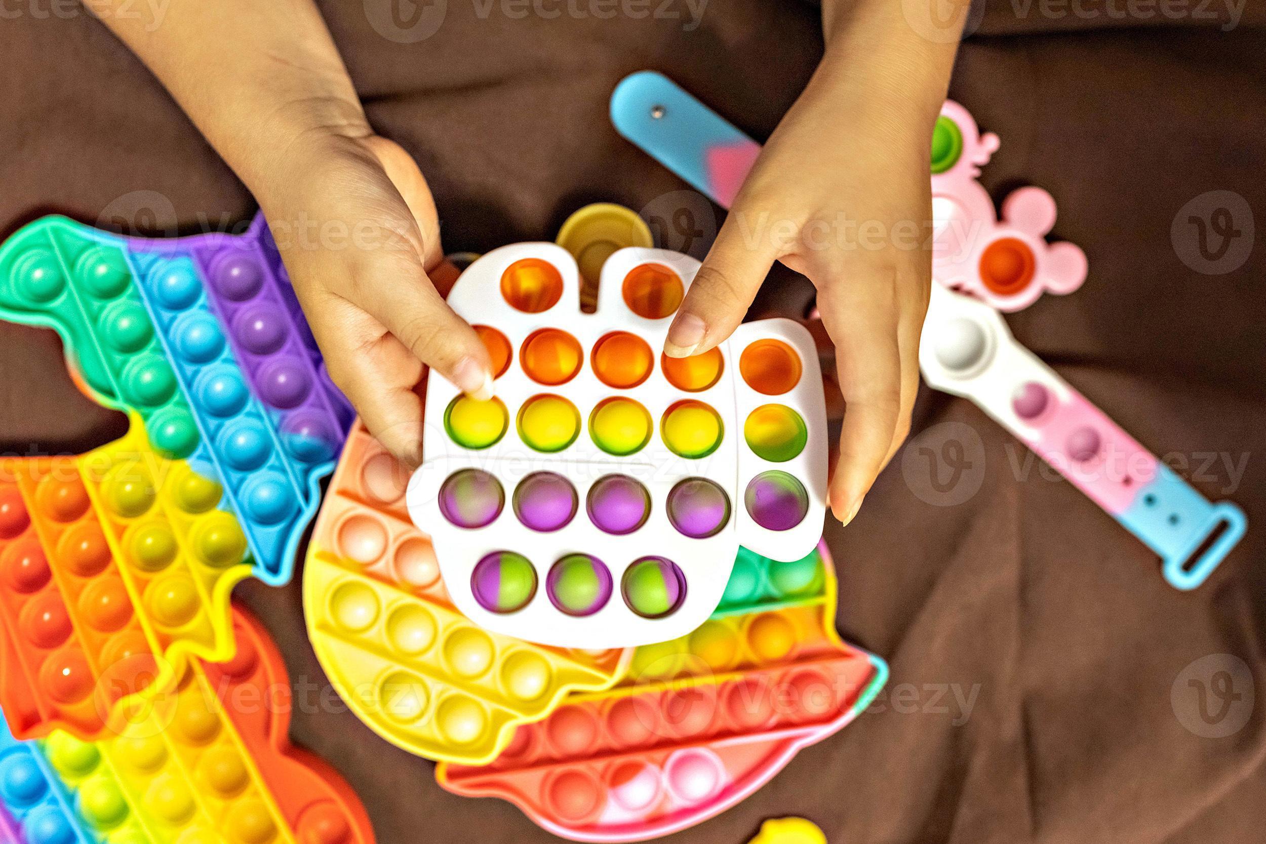 pop it ist ein buntes Anti-Stress-Spielzeug in Kinderhänden. Blasenspiel.  Anti-Stress-Spielzeug. 15601522 Stock-Photo bei Vecteezy