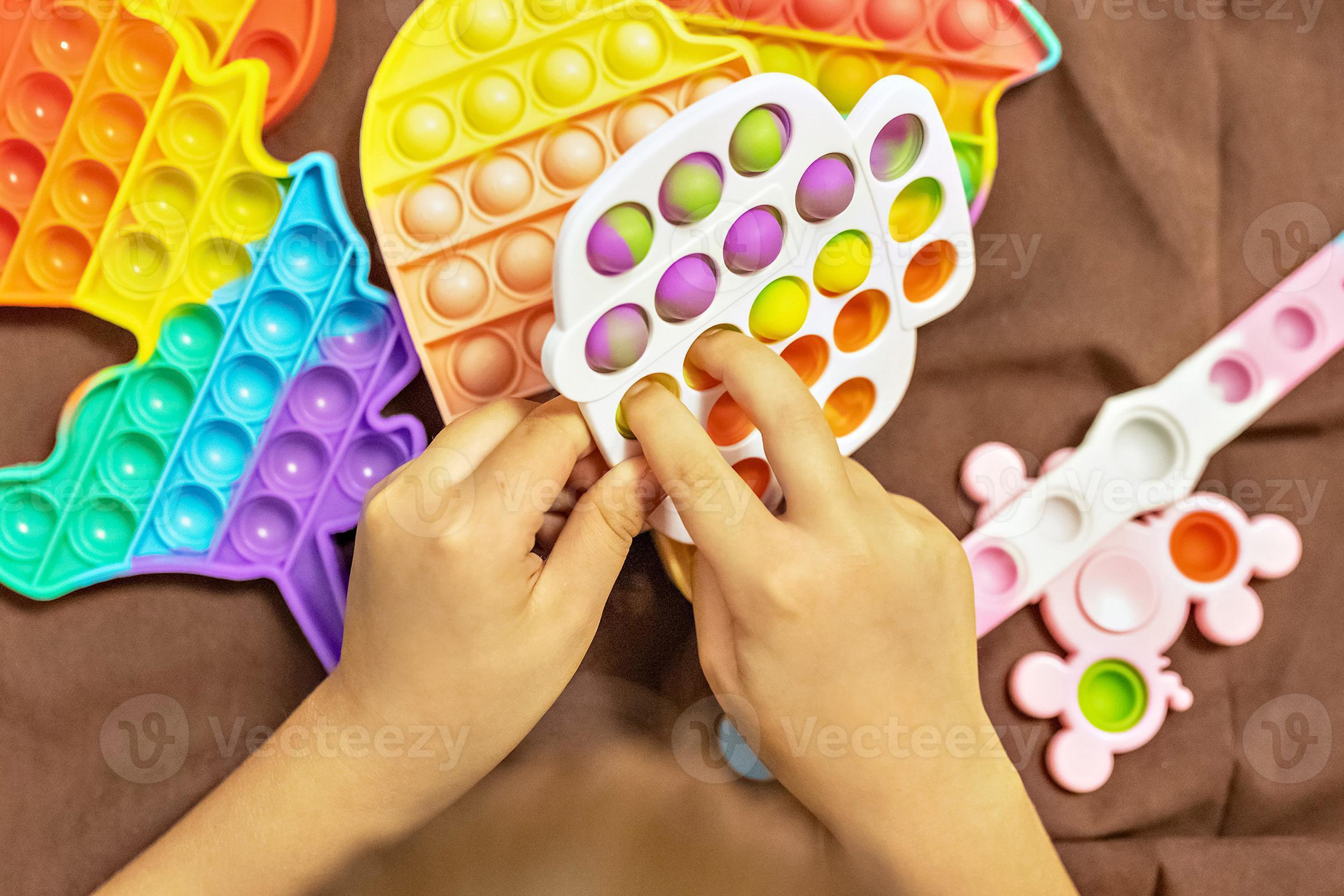 pop it ist ein buntes Anti-Stress-Spielzeug in Kinderhänden. Blasenspiel.  Anti-Stress-Spielzeug. 15938153 Stock-Photo bei Vecteezy