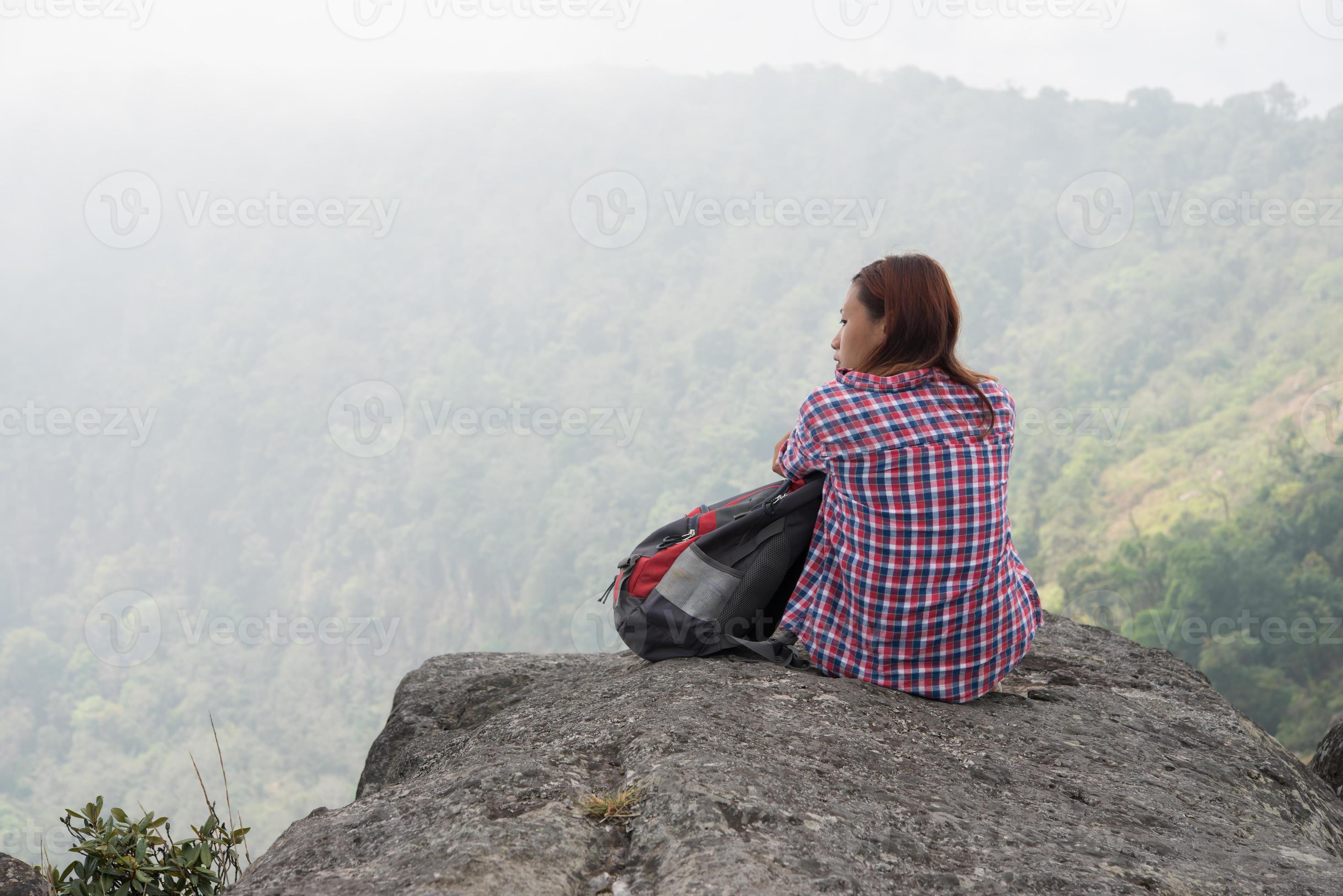 junger Wanderer mit Rucksack sitzt am Rande der Klippe foto