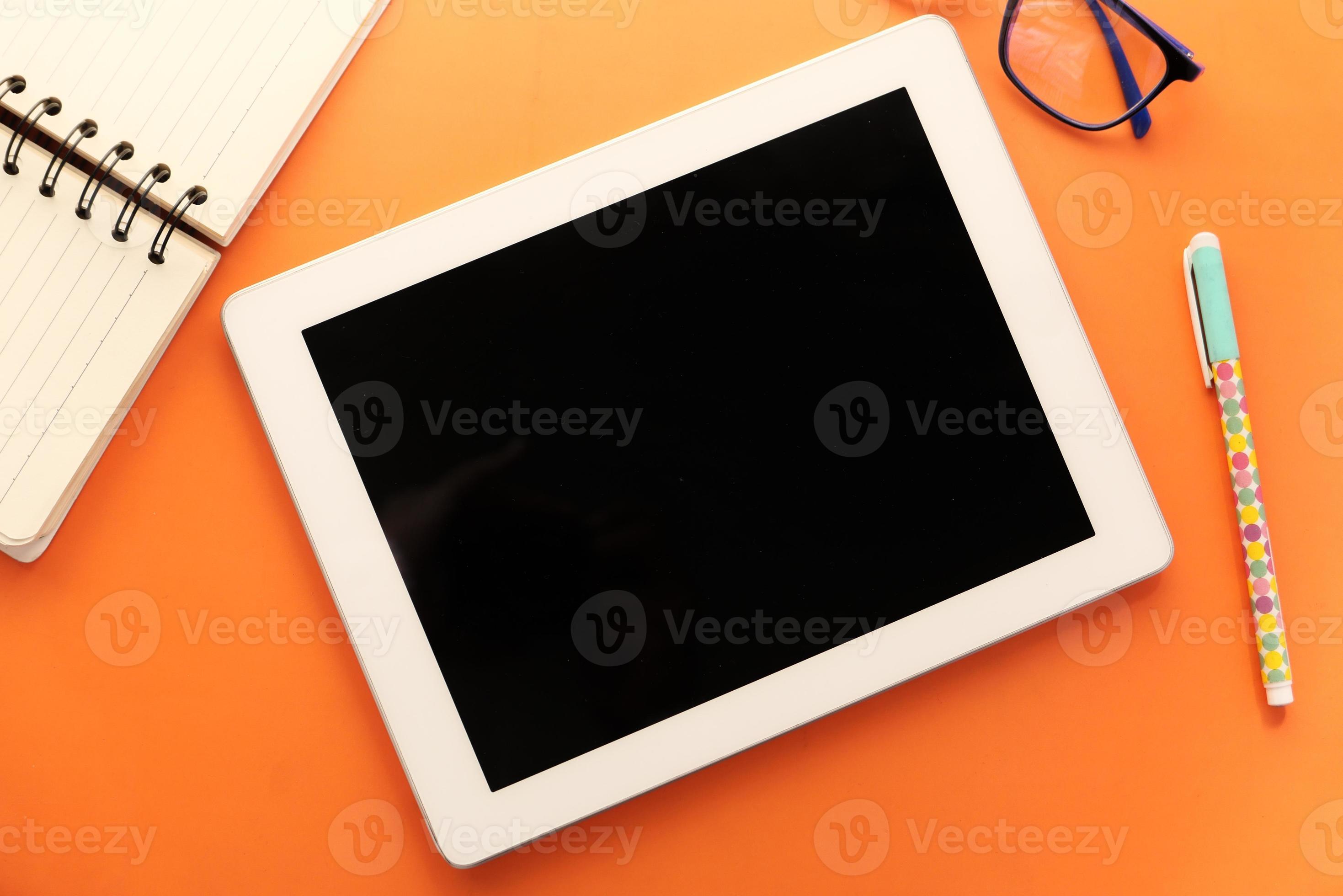 flache Zusammensetzung des digitalen Tabletts und des stationären Büros auf orangefarbenem Hintergrund foto