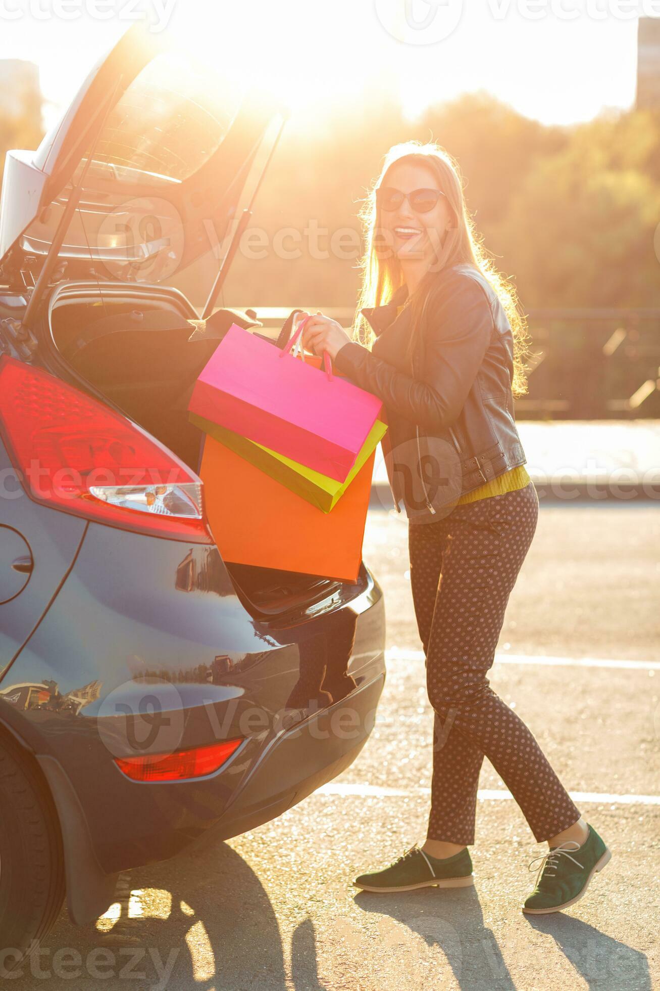 Frau Putten ihr Einkaufen Taschen in das Auto Kofferraum foto