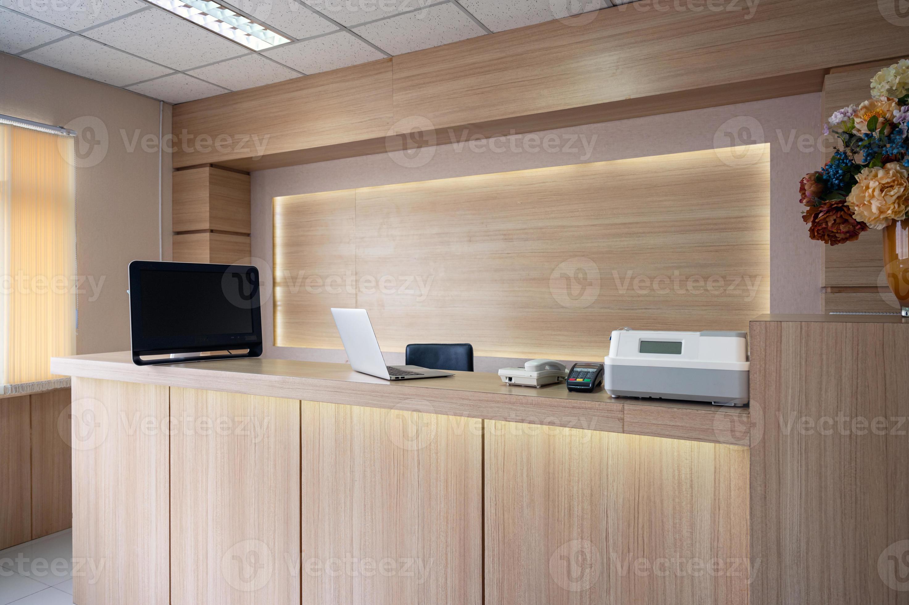 moderner Empfangstresen aus Holz mit Monitor, Laptop und elektronischem Gerät im Krankenhaus foto