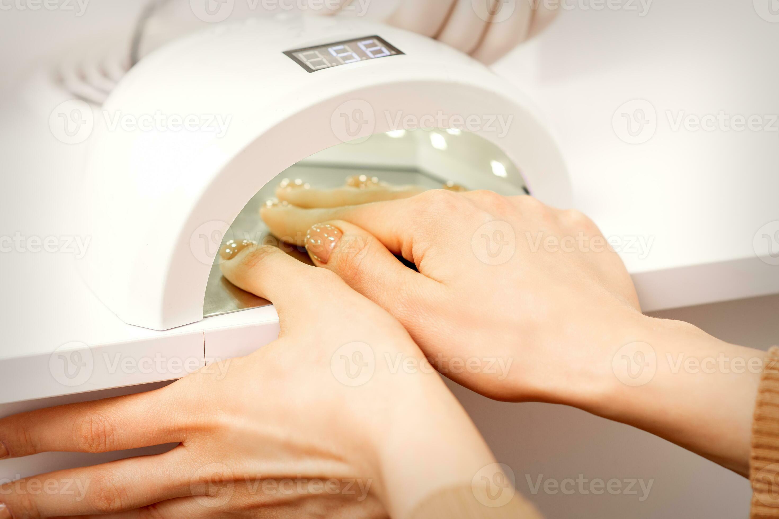 weiblich Hand mit gepflegt Finger trocken Innerhalb uv Licht Maschine im  Maniküre Salon. 26688786 Stock-Photo bei Vecteezy