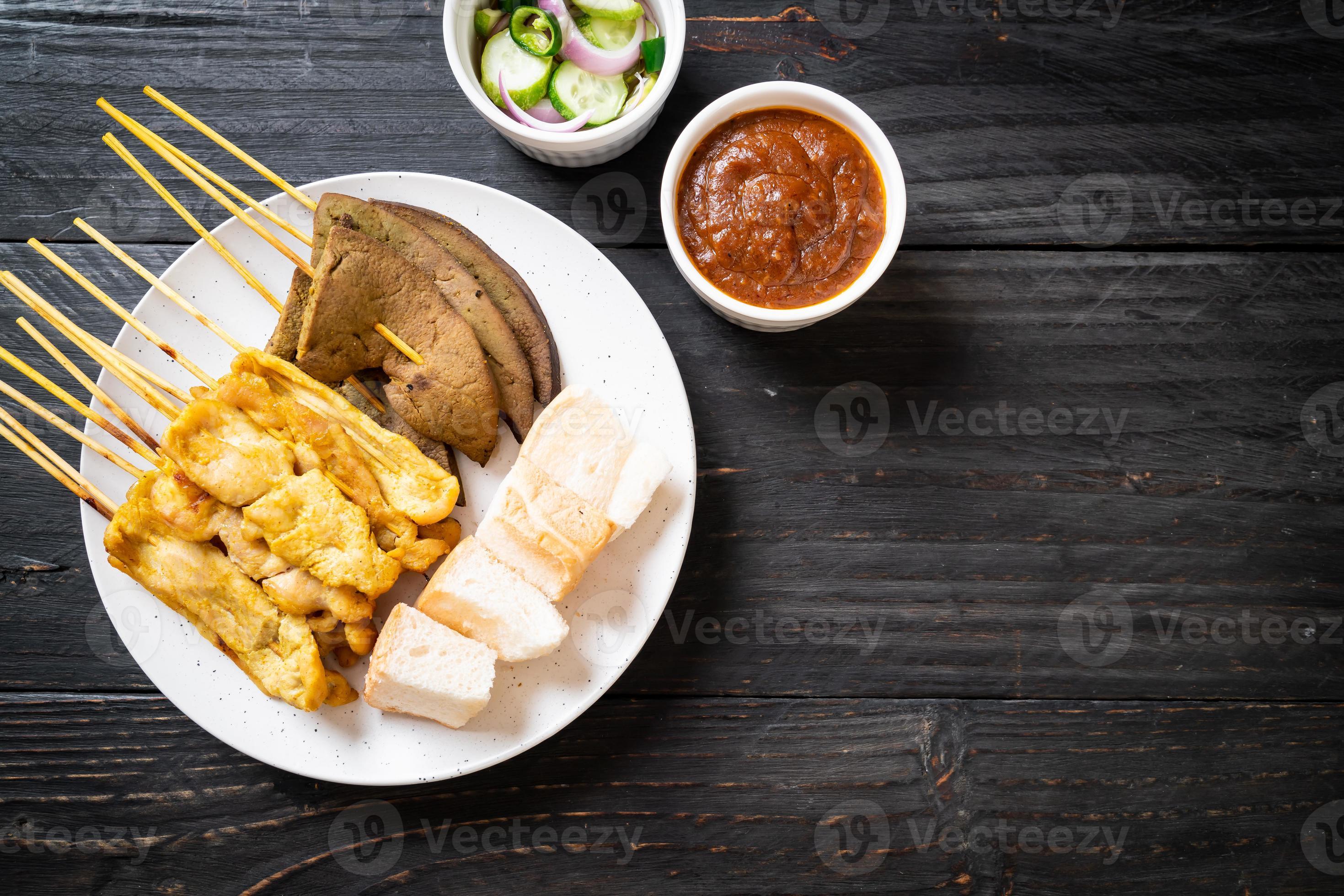 Schweinefleisch-Satay mit Erdnusssauce und Gurken, Gurkenscheiben und Zwiebeln in Essig foto