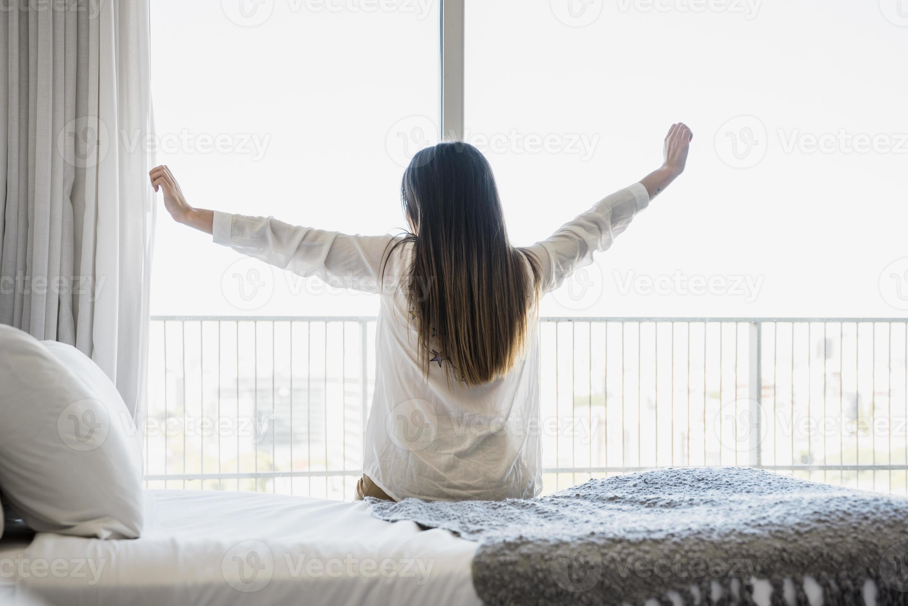 Rückansicht Frau sitzt im Bett und streckt ihre Arme aus. hochwertiges schönes Fotokonzept foto