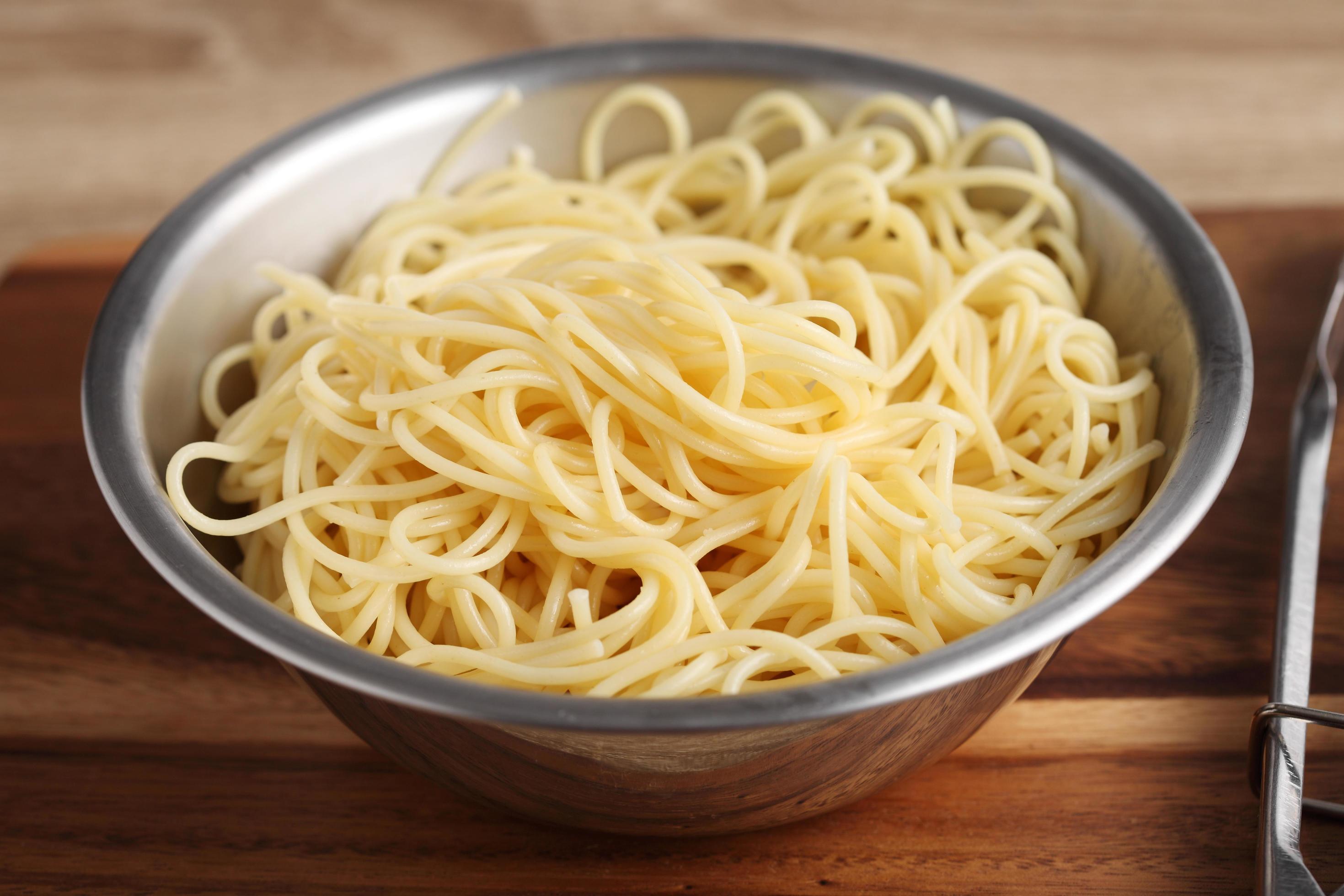 gekochte Spaghetti in Metallschüssel auf Schneidebrett foto
