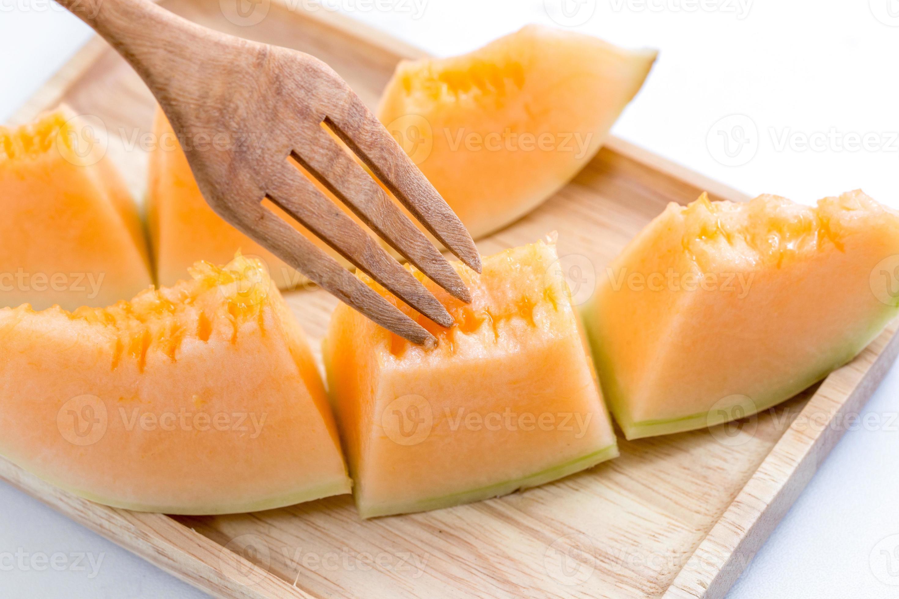 saftige Melone Melone mit Gabel auf einem Holzteller foto