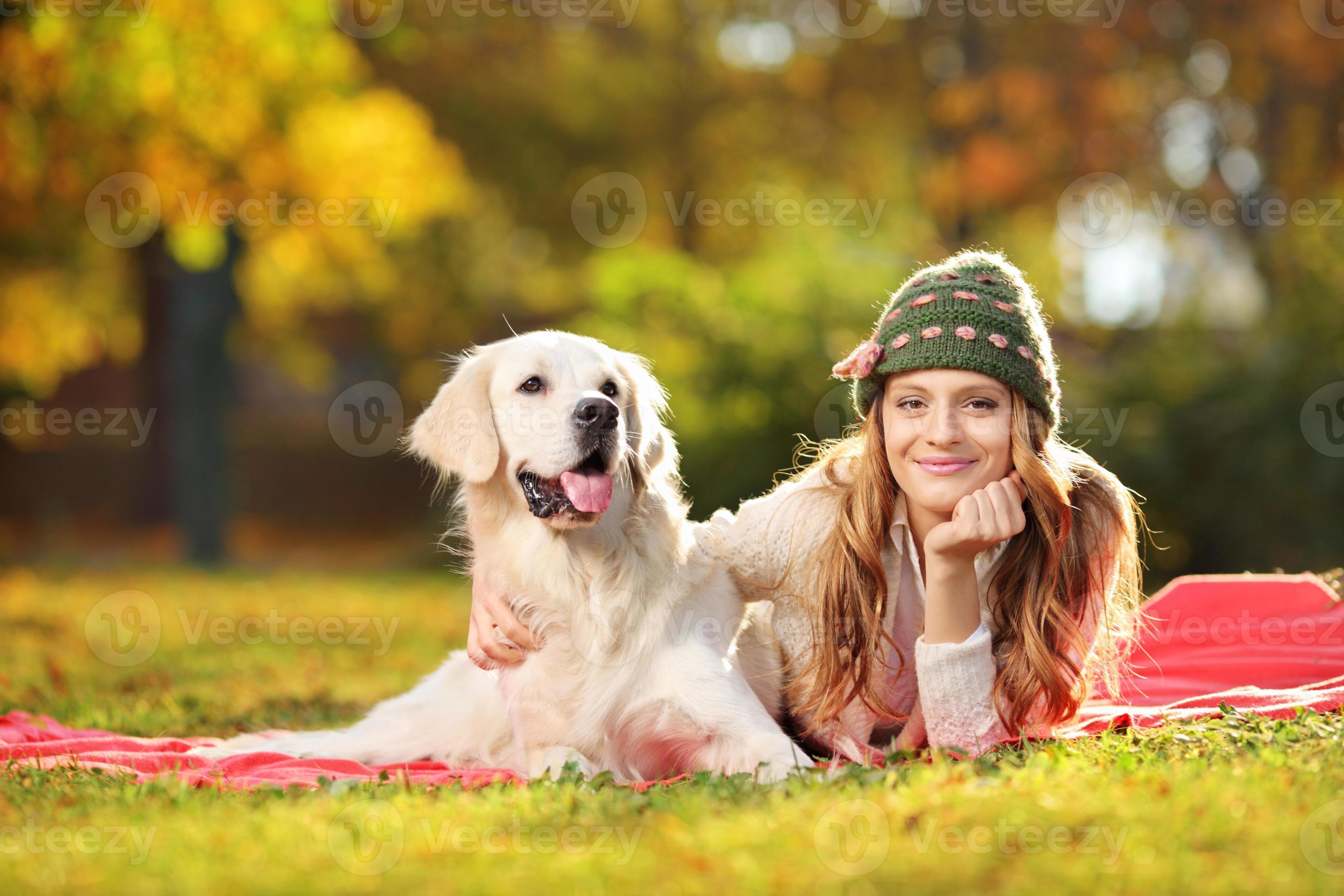 hübsche Frau, die mit ihrem Hund in einem Park liegt foto
