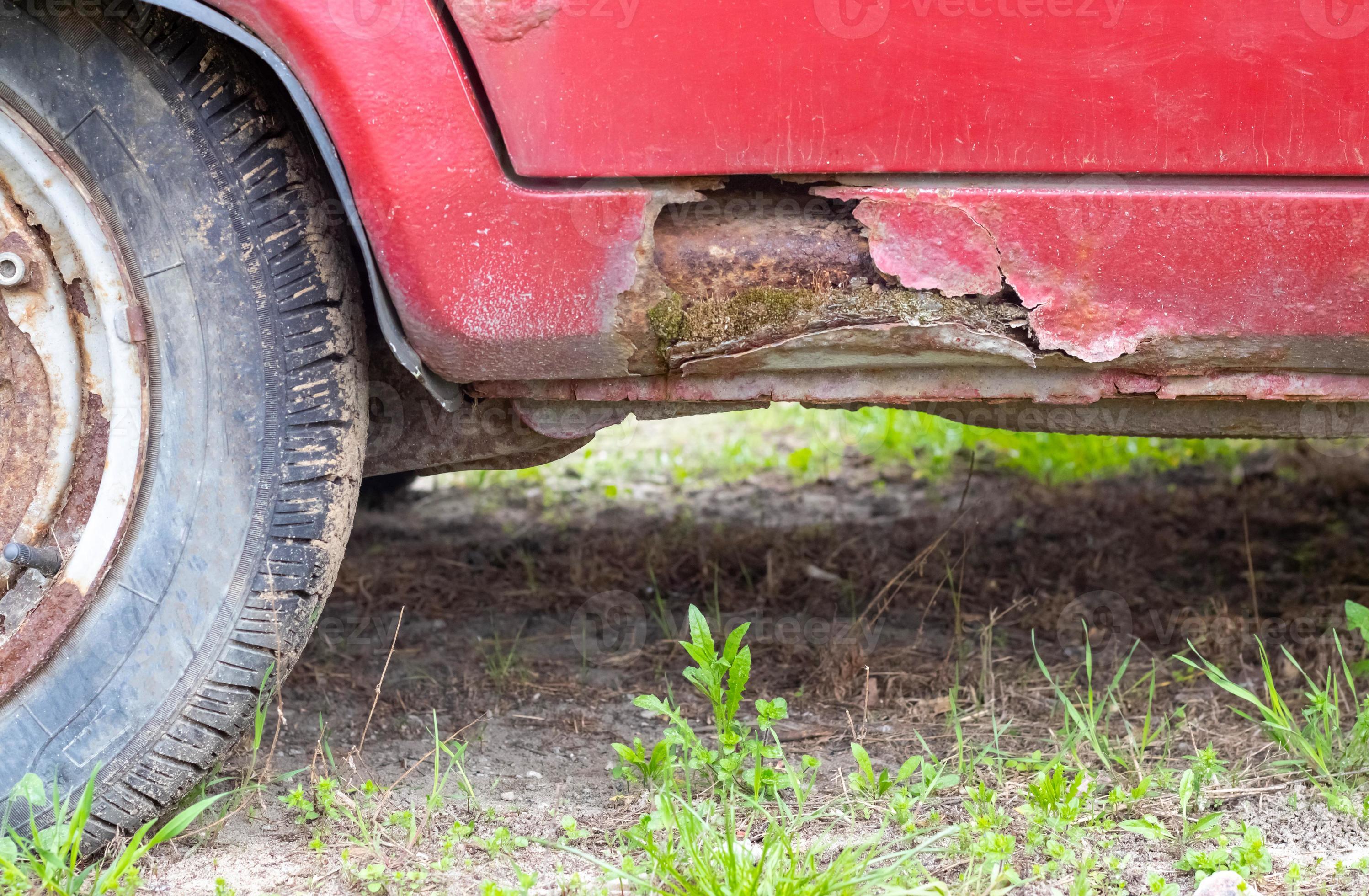 rostige Schweller der Fahrertür. Korrosion der Karosserie eines roten alten  Autos nach dem Winter. Einwirkung von Reagenzien im Winter auf eine  ungeschützte Fahrzeugkarosserie. Beschädigung an der linken Seite, morsche  Schwelle unten. 8945449