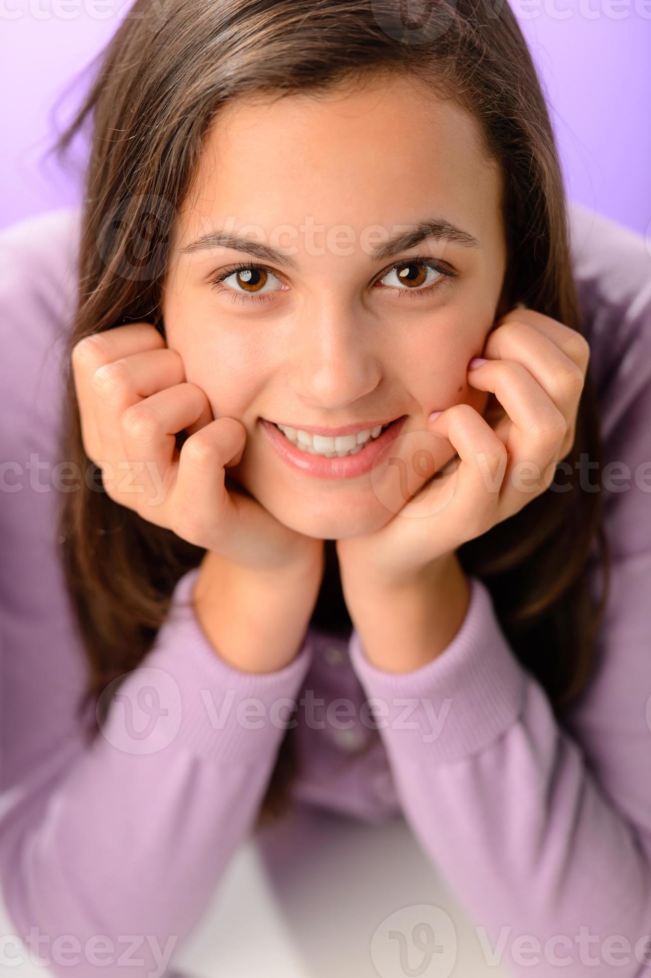 Teenager-Mädchen, das auf lila Nahaufnahmeporträt lächelt foto