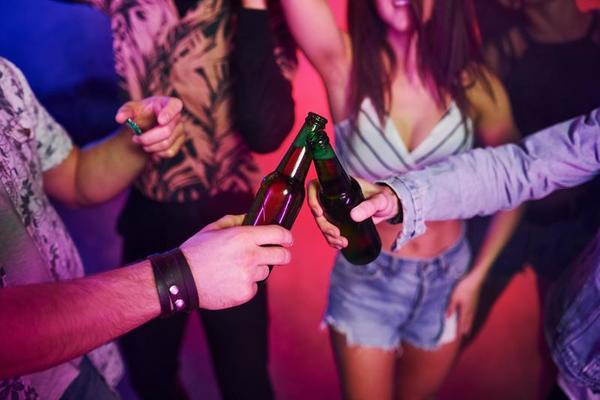 Feiern und Klopfen von Flaschen mit Alkohol. junge leute haben spaß im  nachtclub mit bunten laserlichtern 15255628 Stock-Photo bei Vecteezy