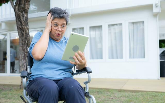 Frau im rollstuhl mit tablette