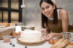 junge schöne frau backt in ihrem küchen-, bäckerei- und cafégeschäft foto