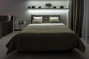 Doppelbett mit Kissen im Inneren des modernen Schlafzimmers in einer Dachgeschosswohnung im hellen Farbstil teurer Wohnungen