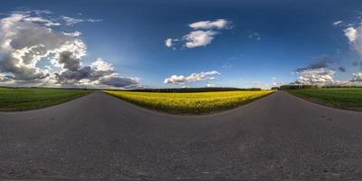 volles sphärisches nahtloses Hdri-Panorama 360-Grad-Winkelansicht auf verkehrsfreier Asphaltstraße in der Nähe von Rapsfeldern mit schwarzem Himmel nach Sturm in equirectangularer Projektion, vr ar-Inhalt foto