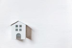 einfach minimalistisches Design mit Miniatur-Spielzeughaus isoliert auf weißem Hintergrund. Hypotheken-Sachversicherung Traumhaus-Konzept. Flache Ansicht von oben, Kopierbereich foto